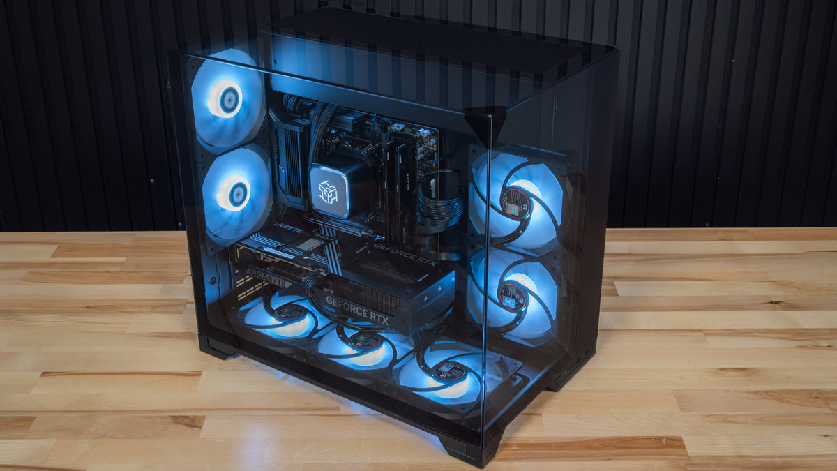 PowerGPU Nox RTX 5070 gaming PC, glossy black case with blue LED fans on a wood floor