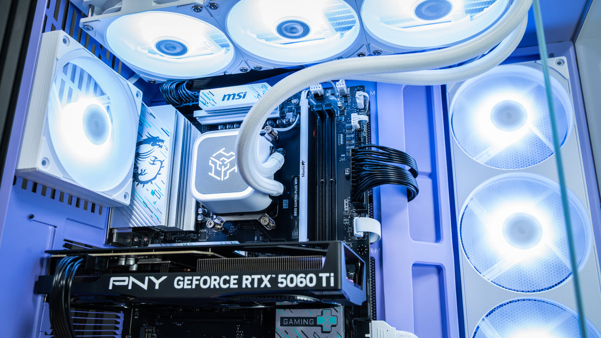Close-up of a custom PC build inside a glass case, featuring a white liquid CPU cooler, MSI motherboard, PNY GeForce RTX 5060 Ti graphics card, and multiple white LED-fanned fans.