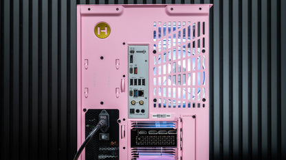 Rear view of a pink desktop PC case with a yellow H logo, showing motherboard I/O ports, power supply intake, and a power cable, against a dark ribbed background