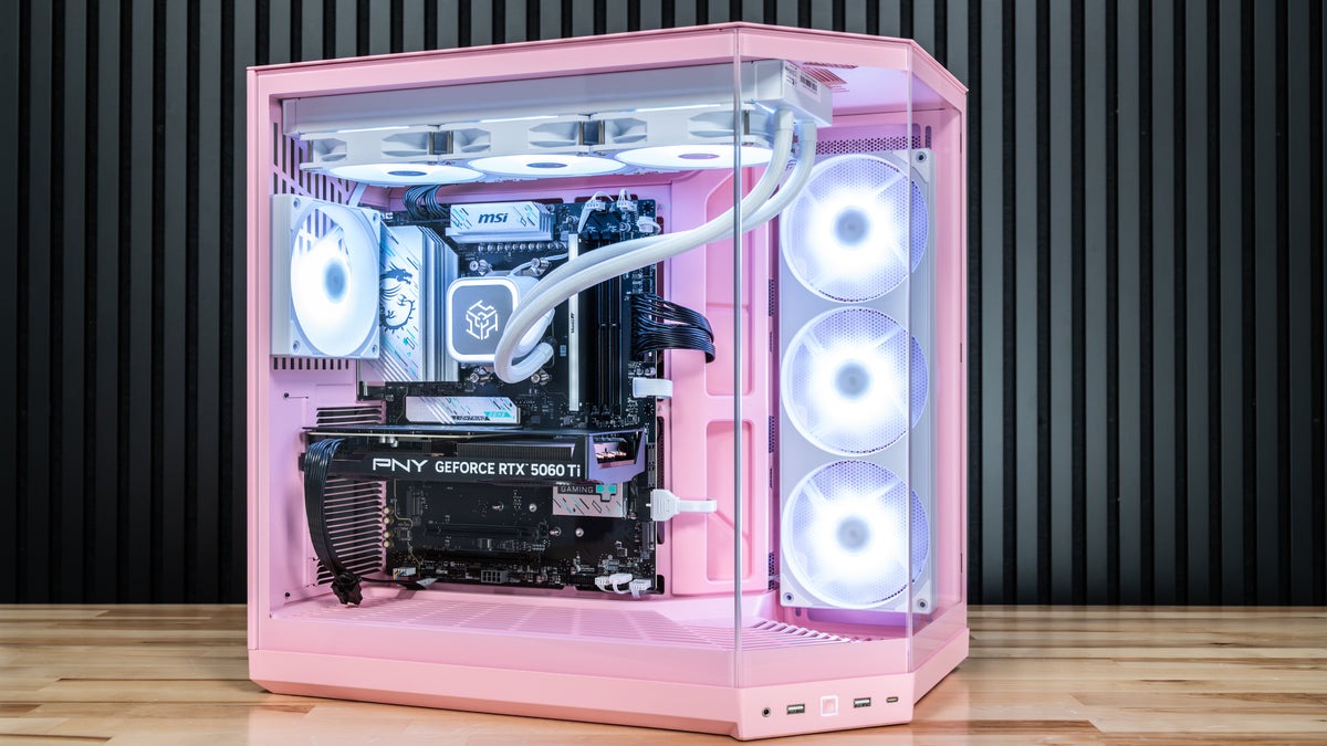 Pink custom PC tower case with a transparent side panel, showcasing a liquid CPU cooler, PNY GeForce RTX 5060 Ti graphics card, and three illuminated white fans, set against a dark wood slatted wall