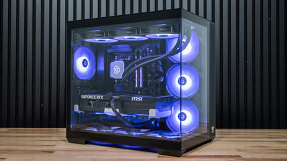 PowerGPU Azul AMD RTX 5090 gaming PC on a wood desk, side view through tempered glass showing blue ARGB fans, liquid-cooled CPU and MSI RTX 5090 GPU